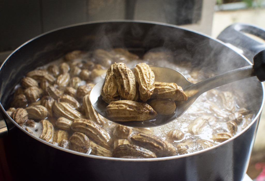 Peanuts boiled in ladle with boiling peanuts as a backdrop.